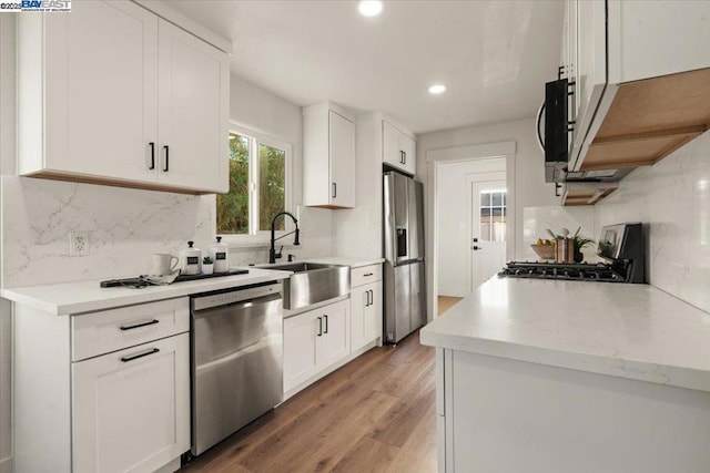 kitchen featuring stainless steel appliances, hardwood / wood-style flooring, sink, and white cabinets