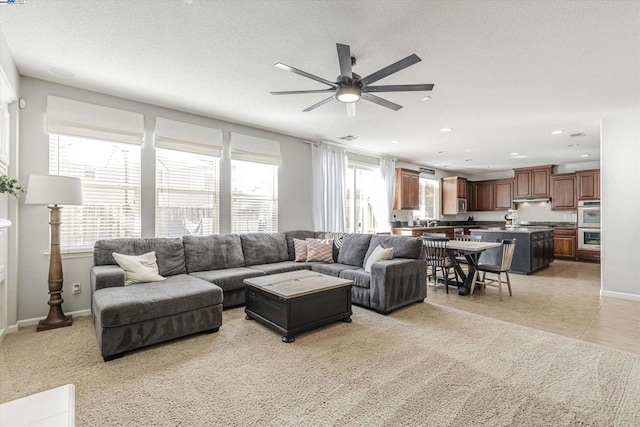 living room featuring light tile patterned floors, a textured ceiling, and ceiling fan