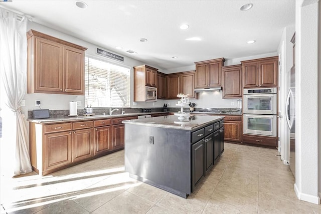 kitchen featuring sink, stainless steel appliances, a center island, and light tile patterned flooring