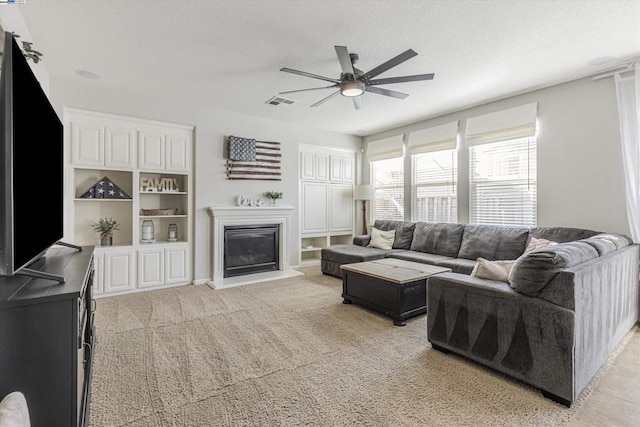 living room featuring light carpet, a textured ceiling, and ceiling fan