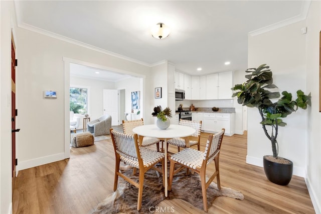 dining area featuring crown molding and light hardwood / wood-style flooring