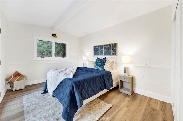 bedroom featuring lofted ceiling with beams and hardwood / wood-style floors