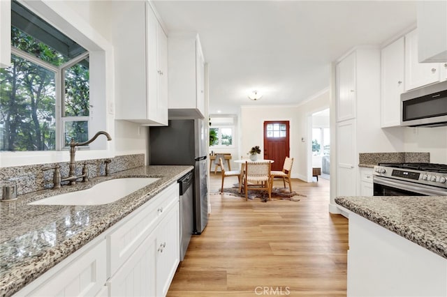 kitchen featuring sink, light stone countertops, white cabinets, and appliances with stainless steel finishes