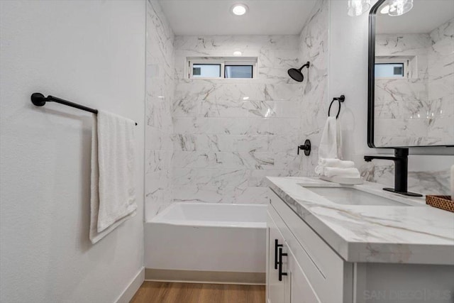 bathroom with hardwood / wood-style flooring, vanity, and tiled shower / bath combo