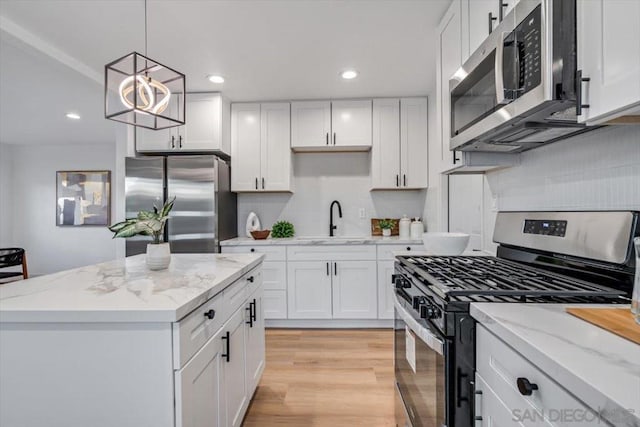 kitchen featuring hanging light fixtures, a center island, white cabinets, and appliances with stainless steel finishes