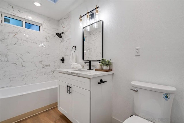 full bathroom featuring vanity, tiled shower / bath, hardwood / wood-style floors, and toilet