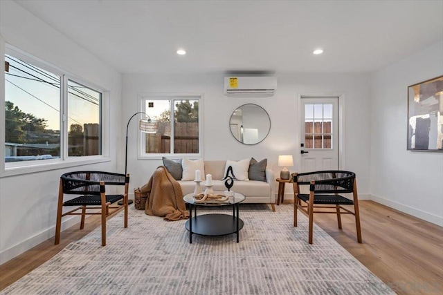 living area with plenty of natural light, light hardwood / wood-style floors, and an AC wall unit