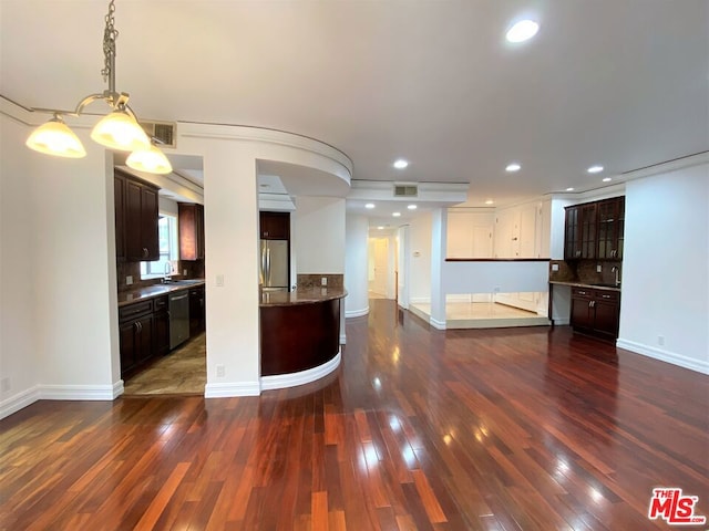 kitchen with appliances with stainless steel finishes, decorative light fixtures, sink, dark brown cabinets, and dark wood-type flooring