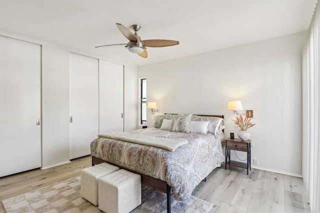 bedroom with two closets, light hardwood / wood-style flooring, and ceiling fan