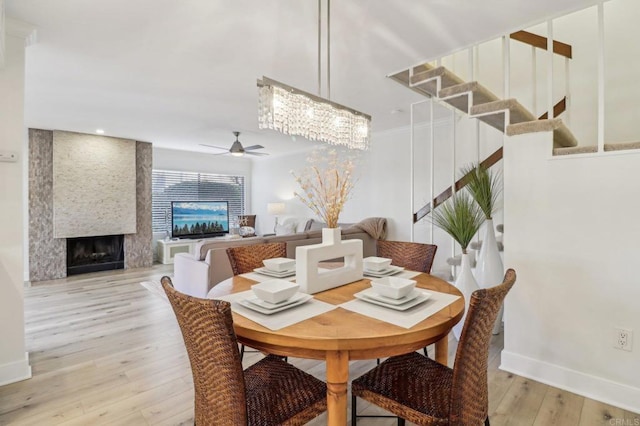 dining area featuring ceiling fan, a fireplace, and light hardwood / wood-style floors