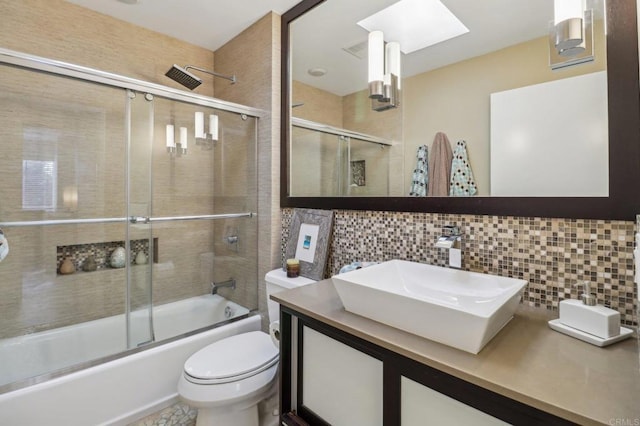 full bathroom with a skylight, shower / bath combination with glass door, decorative backsplash, vanity, and toilet