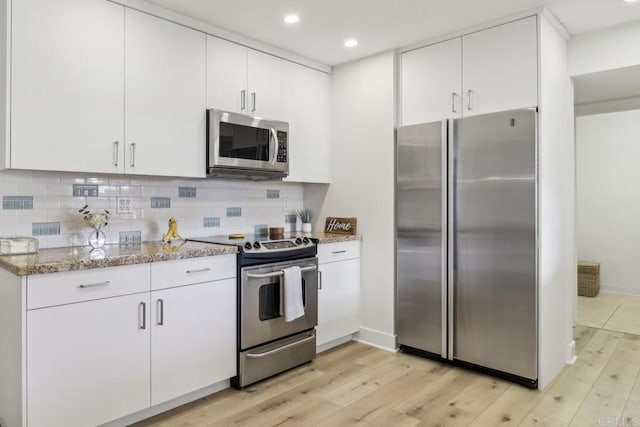 kitchen with white cabinetry, decorative backsplash, stainless steel appliances, and light stone counters