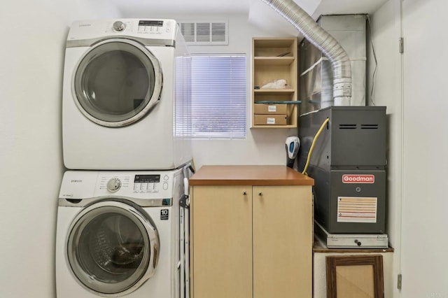 laundry room with cabinets and stacked washer / drying machine