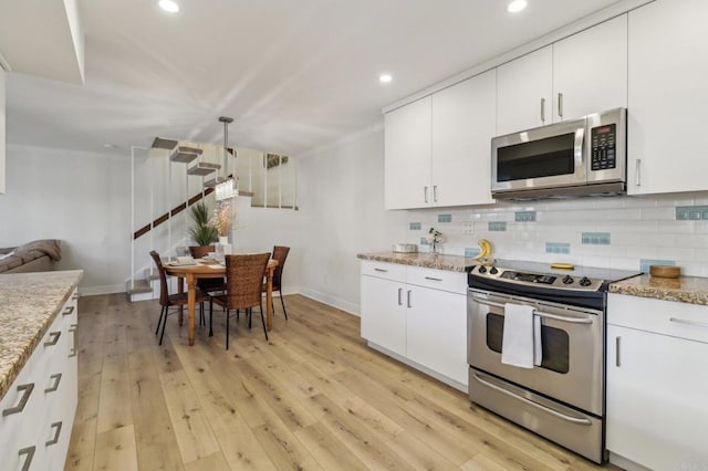 kitchen featuring decorative backsplash, stainless steel appliances, white cabinets, and light wood-type flooring