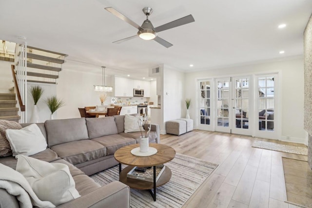 living room featuring ceiling fan, ornamental molding, and light hardwood / wood-style flooring