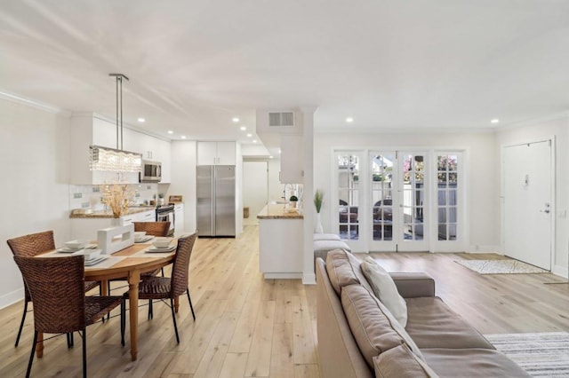 living room featuring crown molding, french doors, and light wood-type flooring