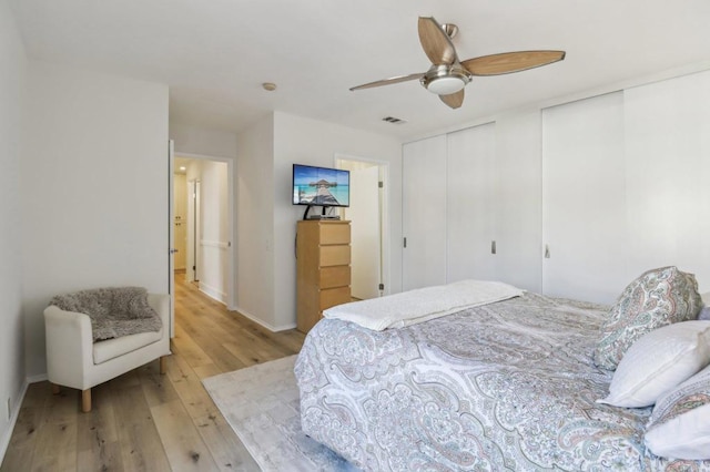 bedroom featuring two closets, light hardwood / wood-style floors, and ceiling fan