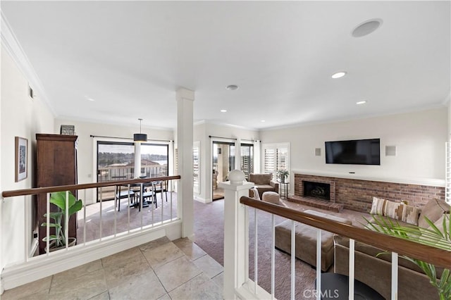 tiled living room featuring a brick fireplace, crown molding, a wealth of natural light, and ornate columns