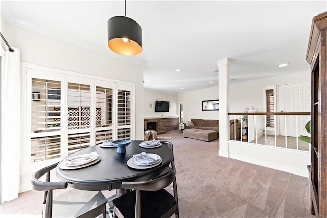 dining area featuring a brick fireplace, ornamental molding, and carpet flooring