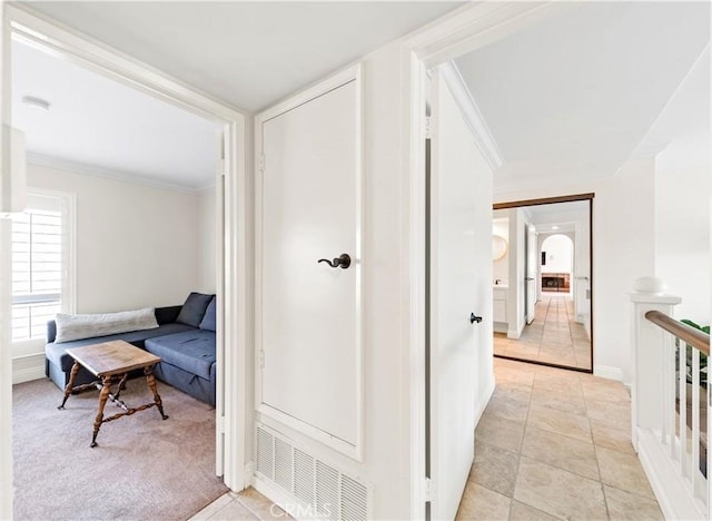 corridor with ornamental molding and light tile patterned flooring