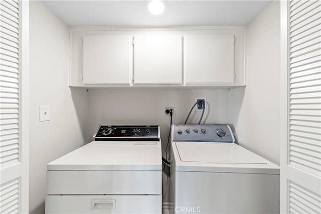 clothes washing area featuring cabinets and separate washer and dryer