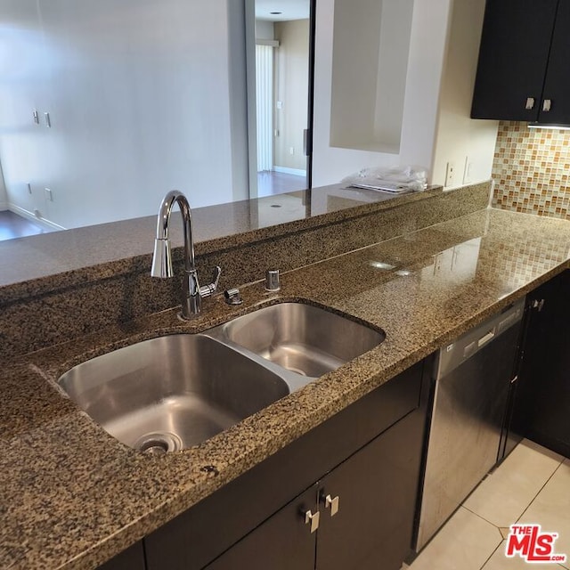 kitchen featuring dishwashing machine, sink, tasteful backsplash, light tile patterned flooring, and dark stone counters