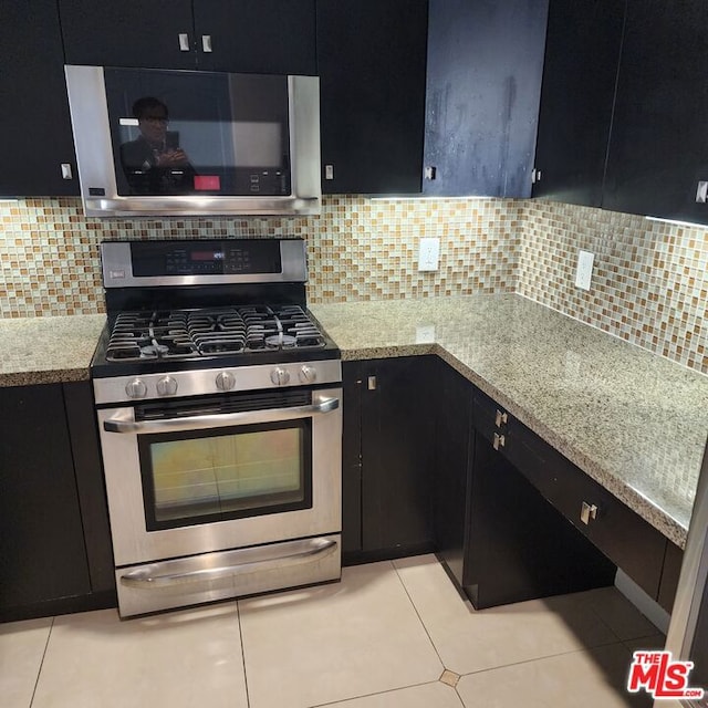 kitchen with appliances with stainless steel finishes, light tile patterned floors, and backsplash