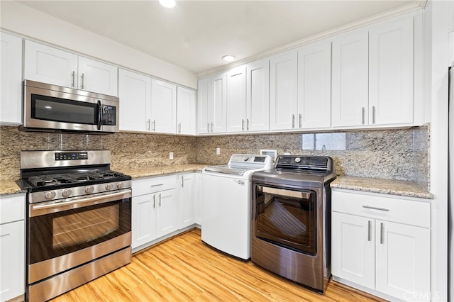 laundry area featuring washing machine and dryer and light hardwood / wood-style flooring