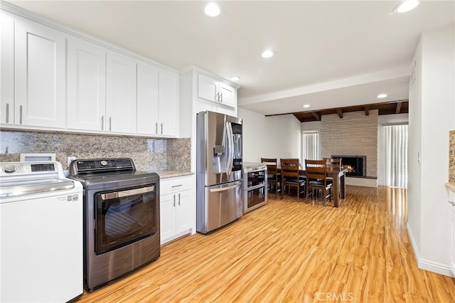 kitchen featuring stainless steel refrigerator with ice dispenser, light wood-type flooring, independent washer and dryer, beam ceiling, and white cabinets