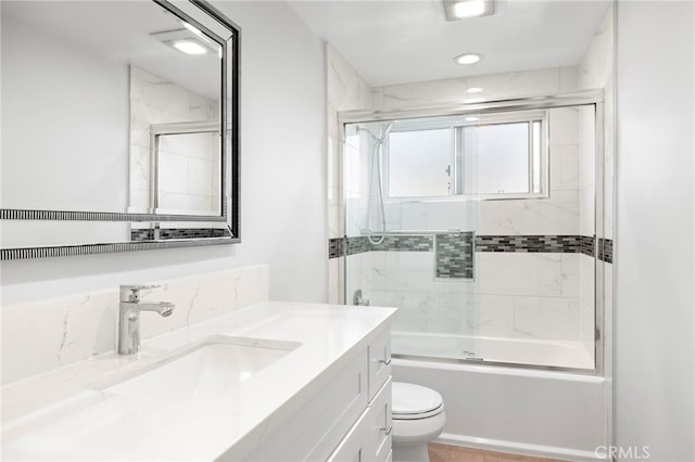 full bathroom featuring enclosed tub / shower combo, vanity, and toilet