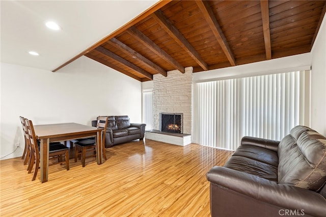 living room with wood ceiling, a fireplace, light hardwood / wood-style flooring, and vaulted ceiling with beams