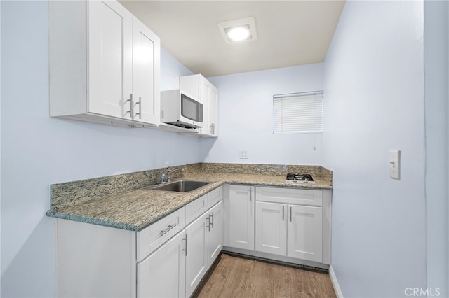 kitchen featuring white cabinetry, sink, hardwood / wood-style flooring, and light stone countertops