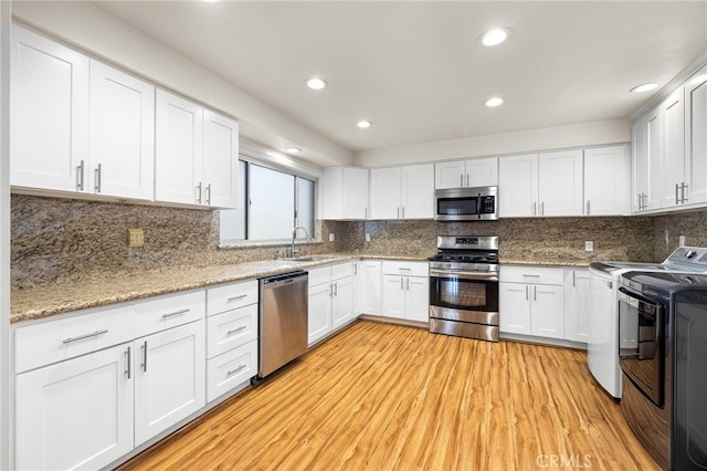 kitchen with washer / clothes dryer, sink, stainless steel appliances, and white cabinets