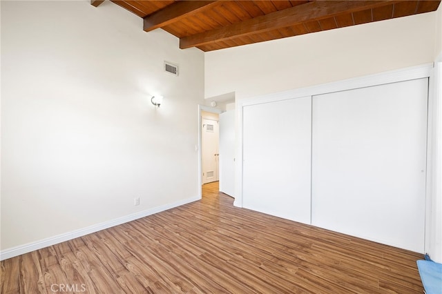 unfurnished bedroom featuring high vaulted ceiling, light hardwood / wood-style flooring, wooden ceiling, a closet, and beamed ceiling