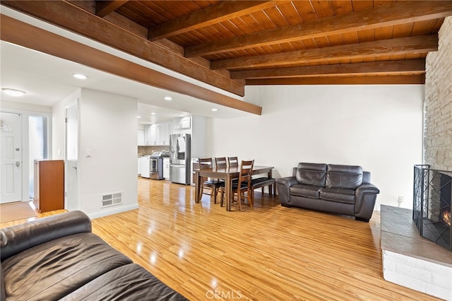 living room with wood ceiling, a fireplace, lofted ceiling with beams, and light wood-type flooring