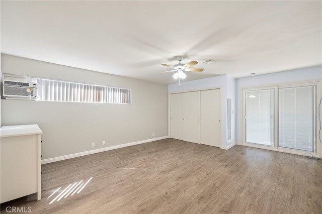 unfurnished bedroom featuring ceiling fan, a wall unit AC, a closet, and light hardwood / wood-style flooring