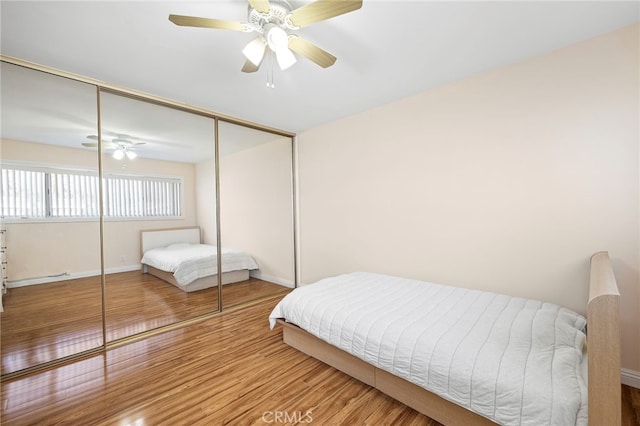 bedroom featuring wood-type flooring, ceiling fan, and a closet