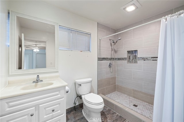 bathroom with a shower with curtain, vanity, ceiling fan, and toilet