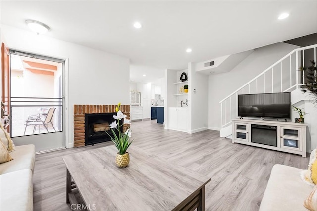 living room featuring light hardwood / wood-style floors and a brick fireplace