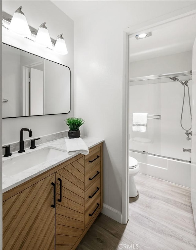 full bathroom featuring vanity, wood-type flooring, shower / bath combination with glass door, and toilet