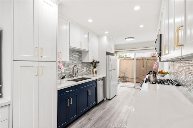 kitchen featuring blue cabinetry, sink, white cabinetry, light hardwood / wood-style flooring, and stainless steel appliances