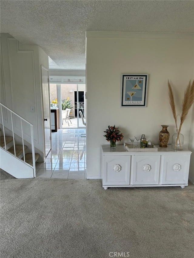 corridor featuring crown molding, light colored carpet, and a textured ceiling