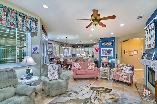 living room featuring ceiling fan with notable chandelier