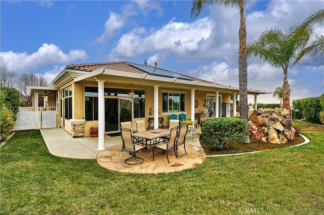 back of property featuring a patio, a yard, and solar panels