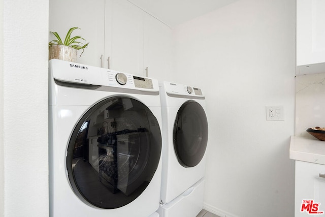 clothes washing area with cabinets and washing machine and dryer