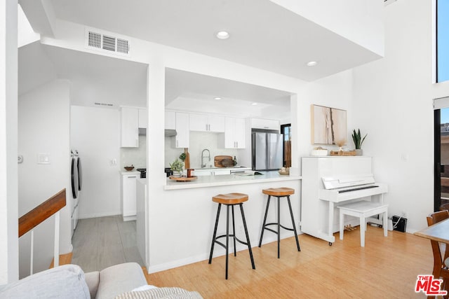 kitchen featuring sink, stainless steel refrigerator, refrigerator, white cabinets, and kitchen peninsula