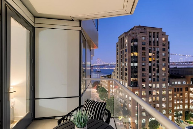 balcony at dusk featuring a water view