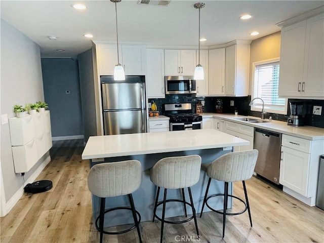 kitchen with a center island, tasteful backsplash, appliances with stainless steel finishes, light wood-style floors, and a sink