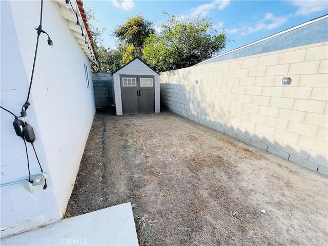 view of yard featuring a fenced backyard, a shed, and an outbuilding