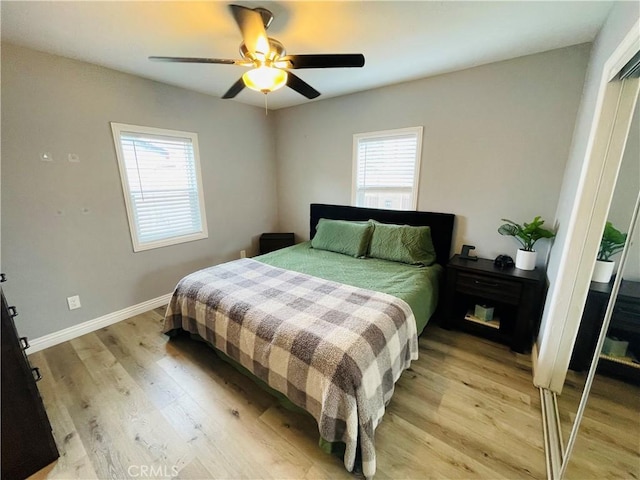 bedroom with light wood-type flooring, multiple windows, ceiling fan, and baseboards